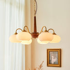 A six-light Clérachic chandelier with cream glass shades hangs beside sheer curtains and a framed vintage print.