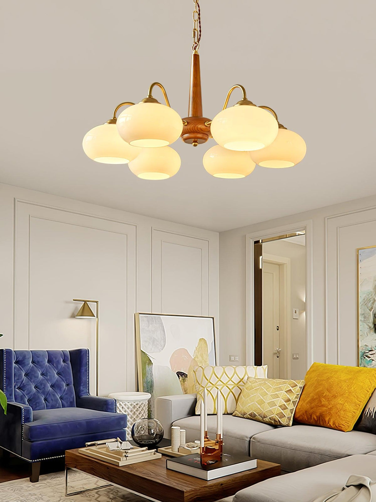 Panelled walls frame this Clérachic chandelier above a living room with a navy tufted armchair and mustard cushions.