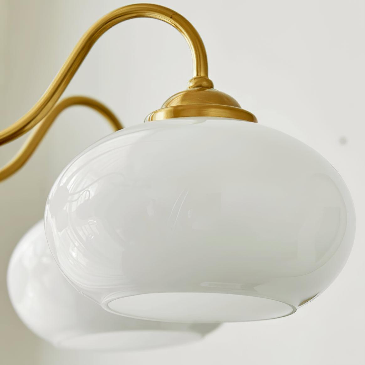 Close view of one glass shade and its brass gallery ring on this Clérachic chandelier.