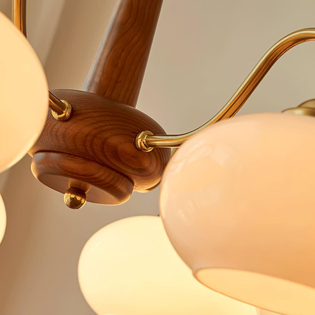 Close view of the walnut hub and brass arm joints on this Clérachic chandelier, showing the glass shade's texture.