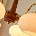 Close view of the walnut hub and brass arm joints on this Clérachic chandelier, showing the glass shade's texture.