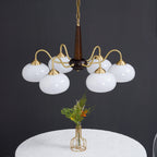 Against a charcoal backdrop, this Clérachic chandelier's white shades hang above a small posy of wildflowers.