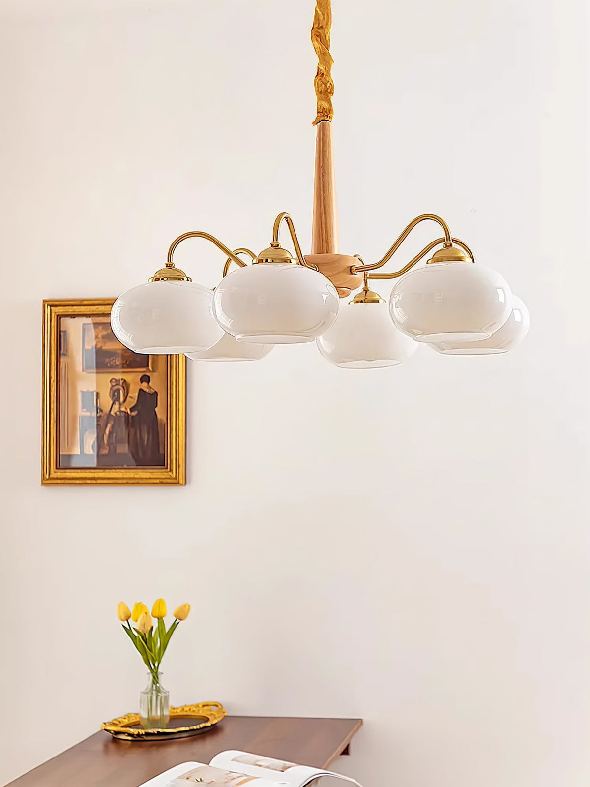 A wider view shows this Clérachic chandelier's four white shades beside the same gilt-framed portrait and tulips.