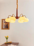 Yellow tulips on a woven tray sit below this Clérachic chandelier, beside a gilt-framed portrait.