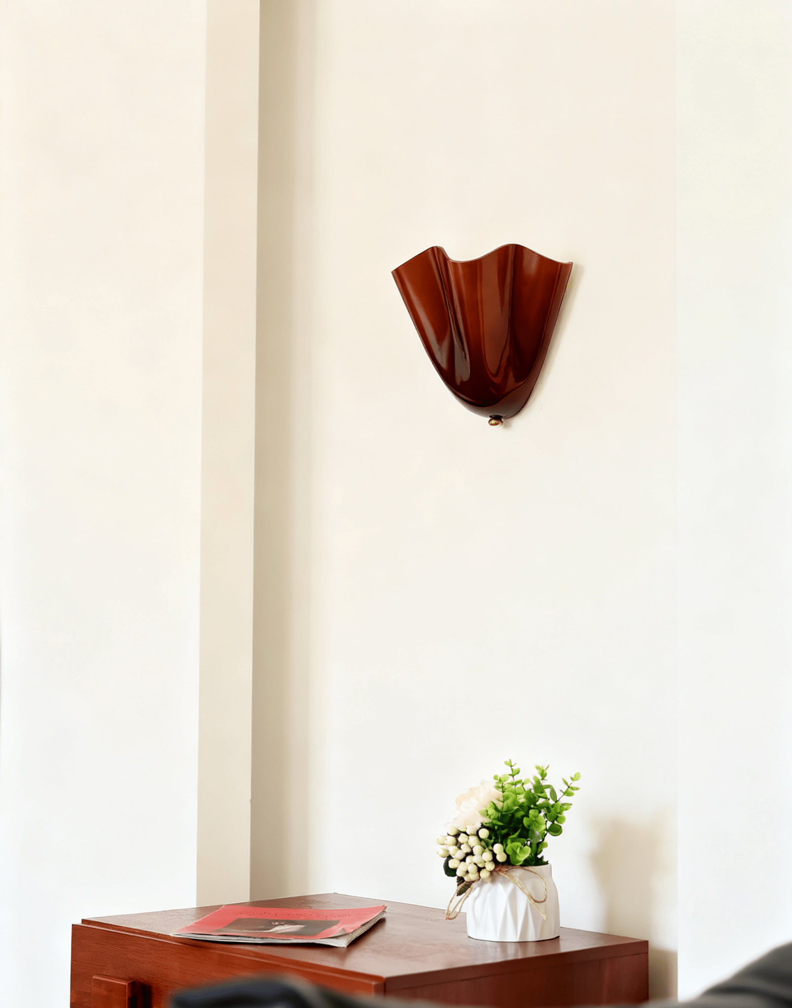 Petalia wall sconce curved shade lit with a gentle warm glow