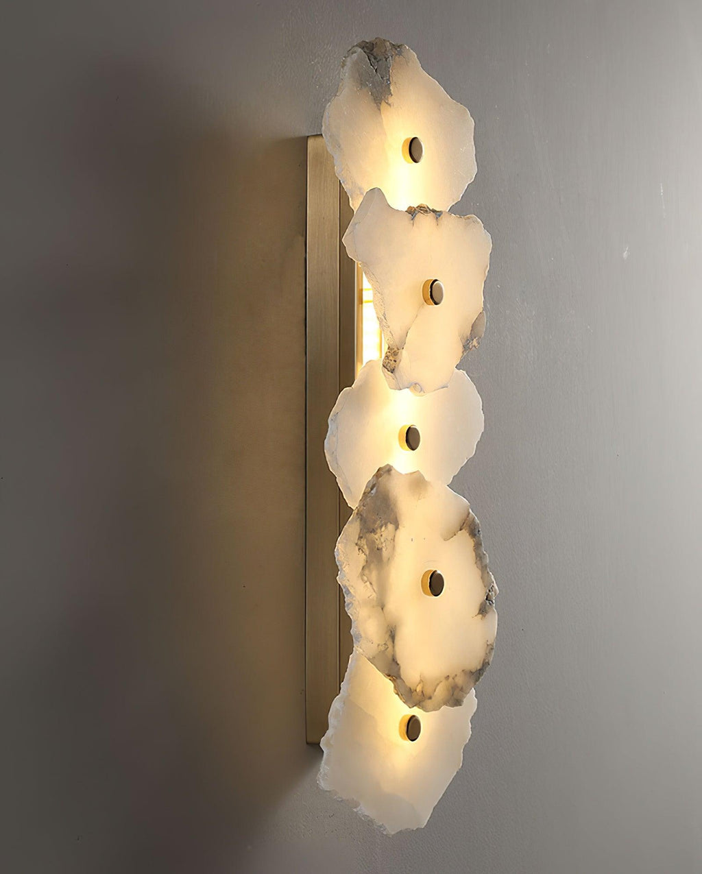 Side view of the Alaeila alabaster wall light showing the slim brass backplate behind the stones.