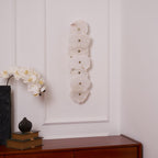 Unlit seven-head alabaster wall lamp in daylight, showing the pale stone and its small brass studs.