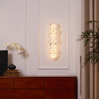 Wide room view of the lit alabaster wall lamp above a wooden sideboard beside a curtained window.