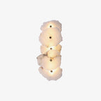 Vertical five-head alabaster wall lamp centred on white, the whole fixture shown lit end to end.