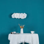 The horizontal alabaster wall lamp switched off on a teal wall, showing the cool white unlit stone.