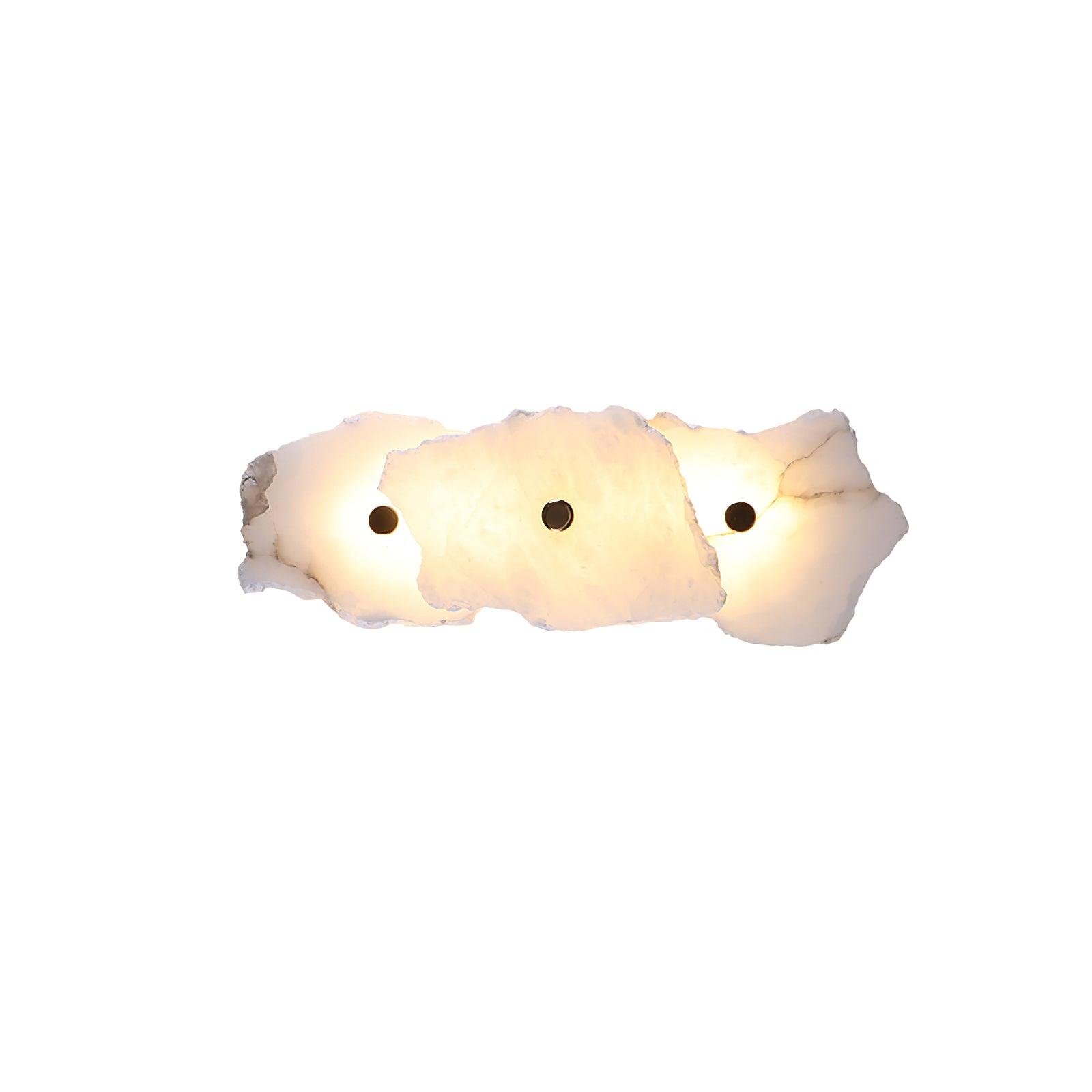 Three overlapping alabaster slabs lit warm, showing the lamp's compact horizontal three-head layout.
