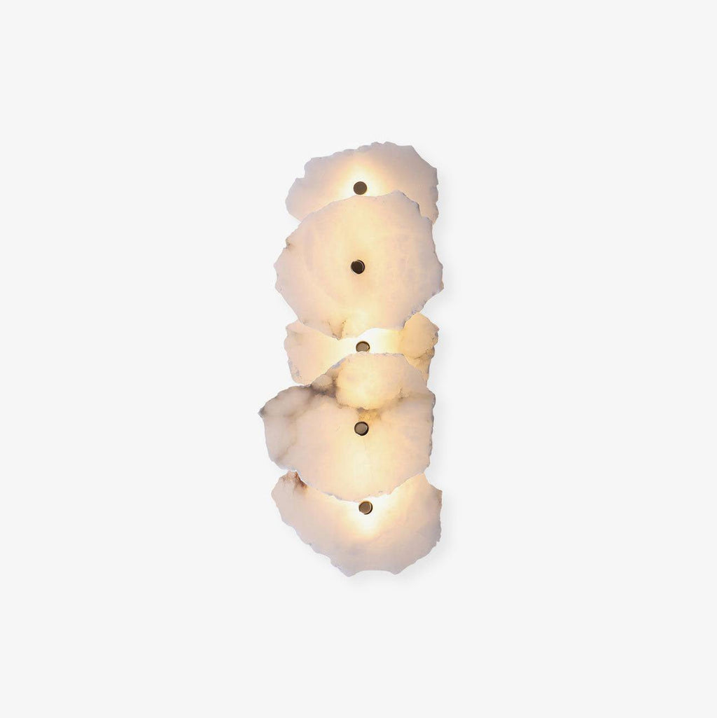 Vertical five-head alabaster wall lamp on a soft off-white background, warm light glowing between slabs.