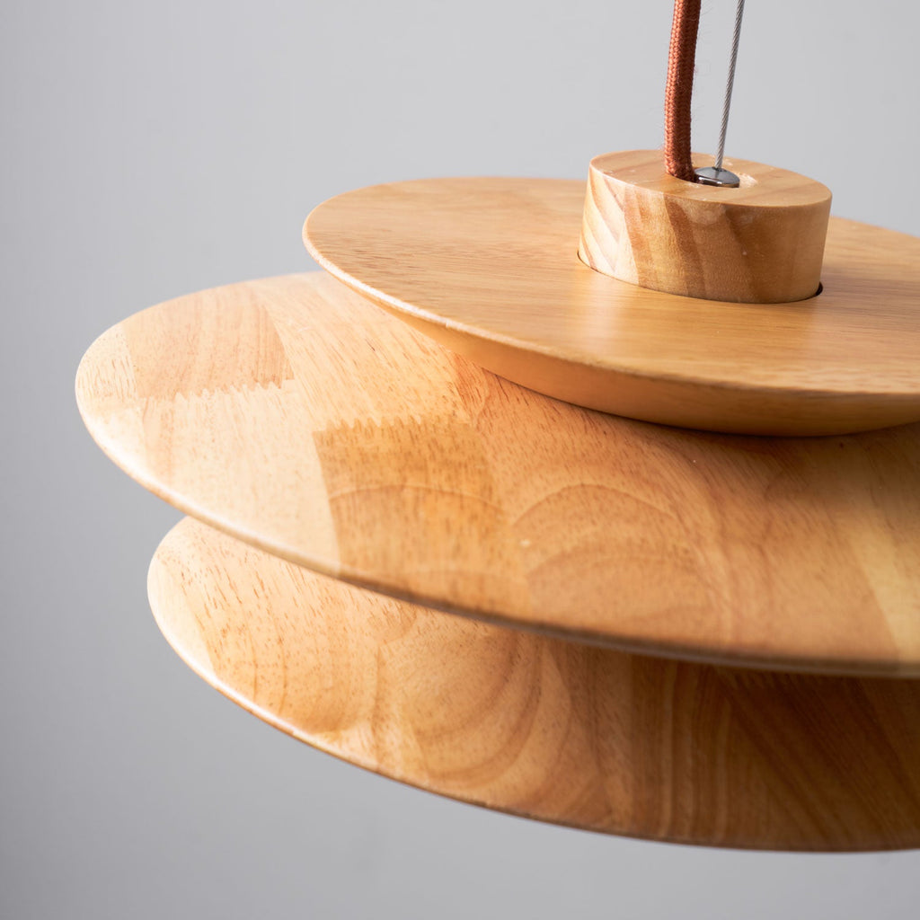 Close view of the wood grain and disc edges on this Clérachic pendant, showing the cord mount at the top of the shade.