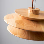 Close view of the wood grain and disc edges on this Clérachic pendant, showing the cord mount at the top of the shade.