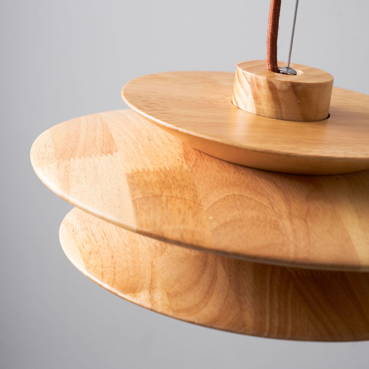 Close view of the wood grain and disc edges on this Clérachic pendant, showing the cord mount at the top of the shade.