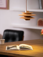 This Clérachic pendant lamp in nature wood is shown above an open book and a small orchid in a bright home office.