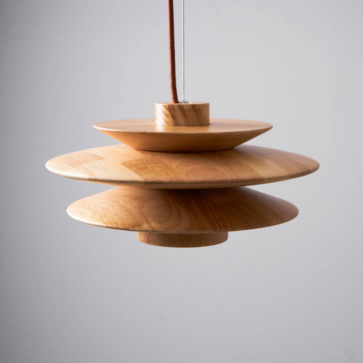 A close view of this Clérachic pendant lamp in nature wood shows its stacked wooden discs and slender cord on a plain grey background.