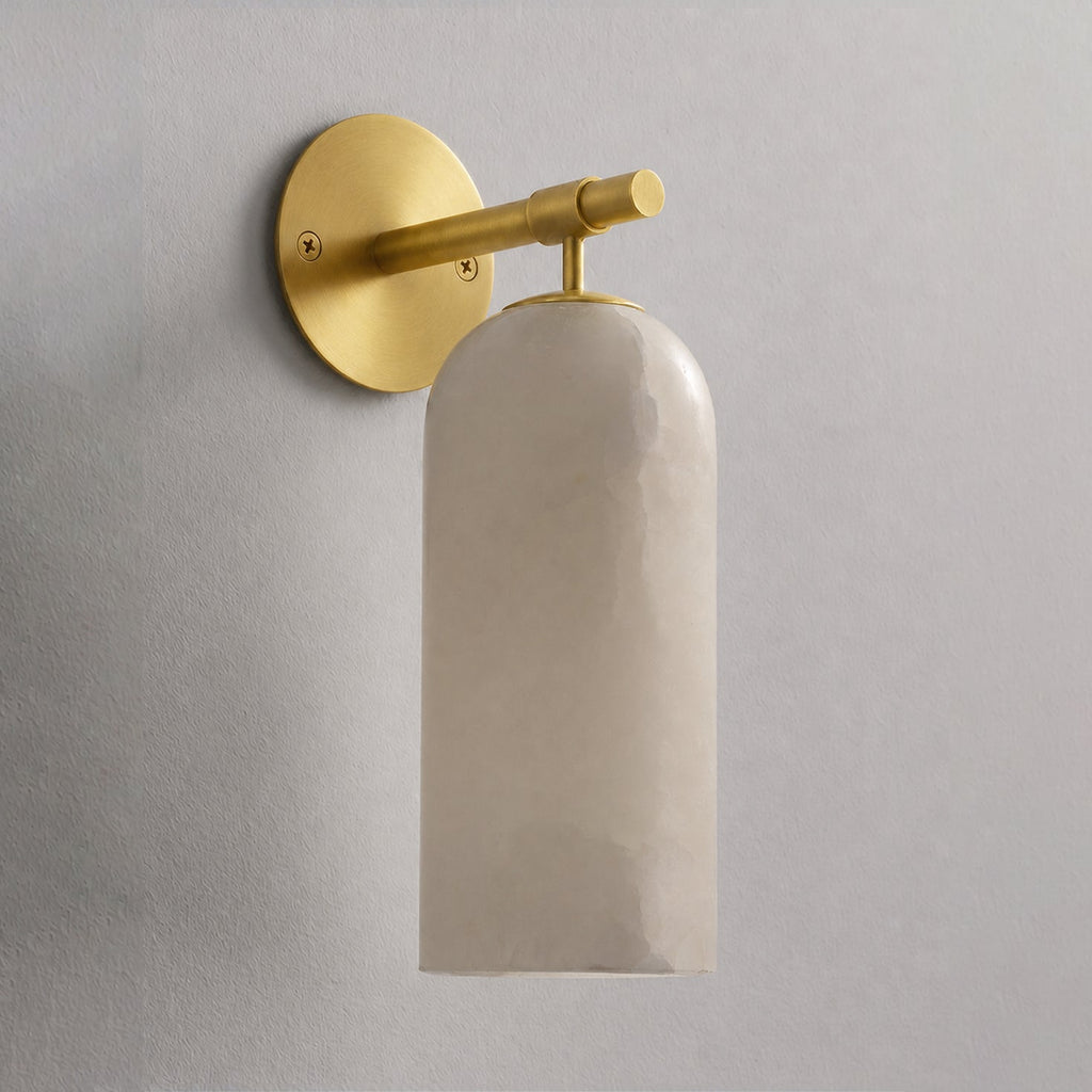 Alabaster cylinder sconce casting soft warm light on the wall