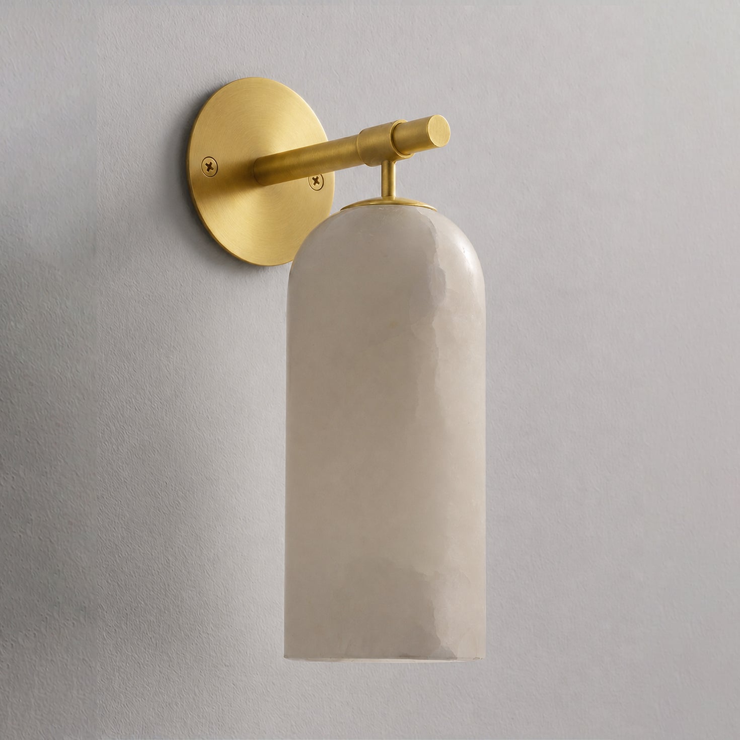 Alabaster cylinder sconce casting soft warm light on the wall