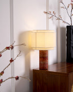 The hexagonal-shade table lamp from Clérachic lit beside a black vase and a cherry-blossom branch on a wood cabinet.
