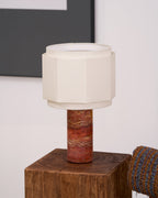 Close crop of the lit hexagonal shade on this Clérachic table lamp, dark framed art blurred in the top corner.
