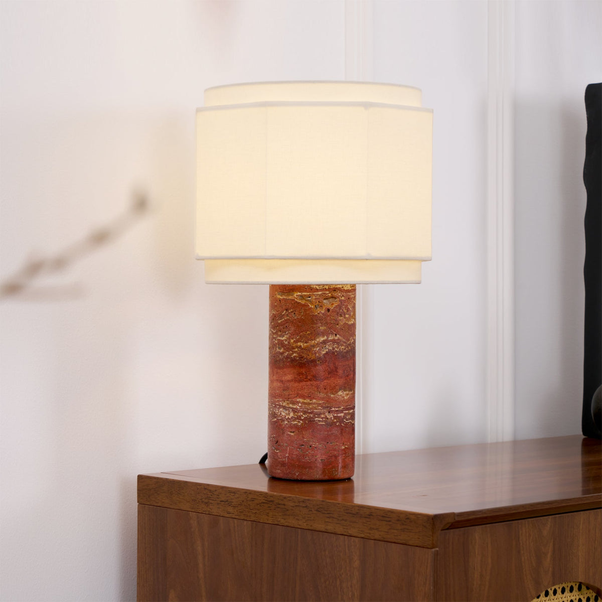 This Clérachic table lamp glows atop a dark wood sideboard, cropped close with a blurred cherry-blossom branch.