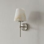 Set against a plain grey wall, this Clérachic wall light shows its alabaster shade in a brushed nickel finish.