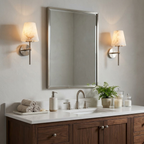 Beside a beveled silver mirror, a pair of brushed nickel Clérachic wall lights flank a dark walnut vanity.