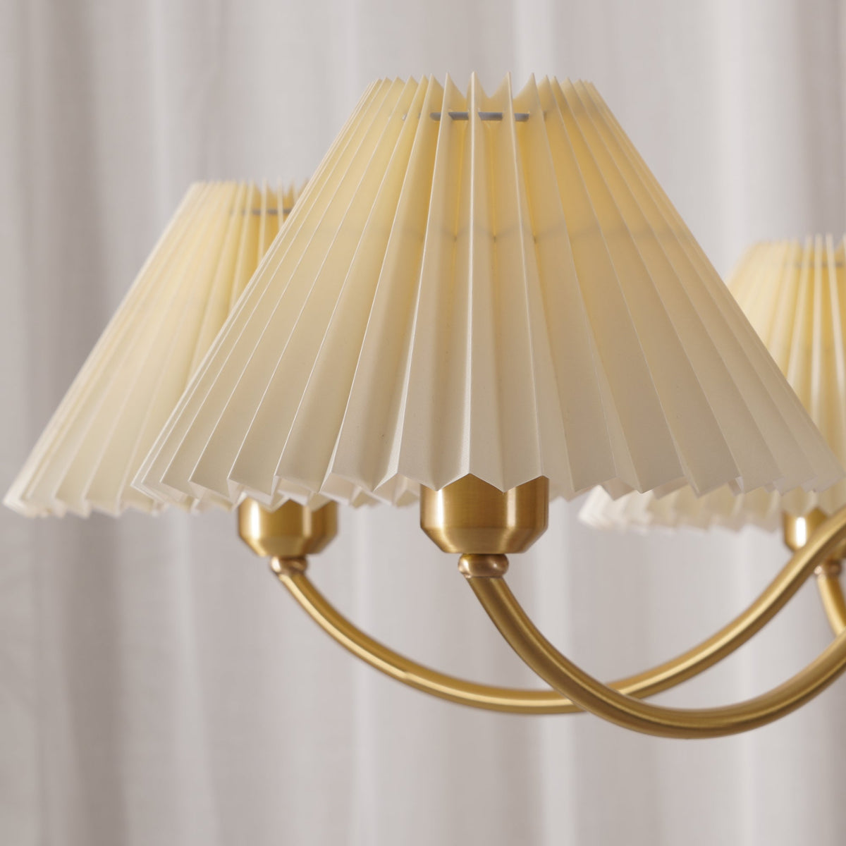 Close view of the fine pleats and brass fittings on this Clérachic chandelier's fabric shades.