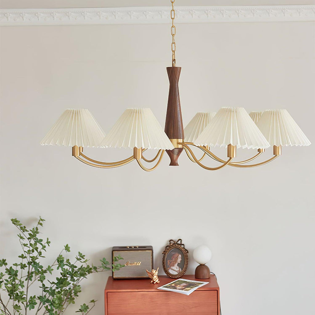 A full arc of pleated shades on this Clérachic chandelier hangs low over a rust-coloured dresser and framed photograph.