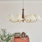 A full arc of pleated shades on this Clérachic chandelier hangs low over a rust-coloured dresser and framed photograph.