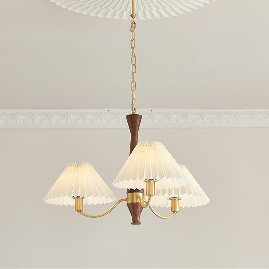 The three-head version of this Clérachic chandelier hangs from a longer chain, crown moulding visible along the ceiling above.