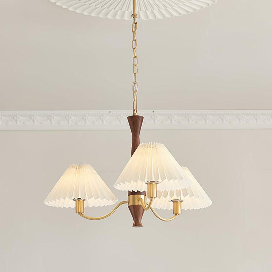 The three-head version of this Clérachic chandelier hangs from a longer chain, crown moulding visible along the ceiling above.