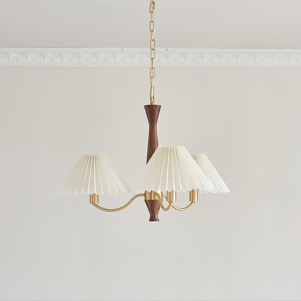 Three ivory pleated shades cluster around the walnut column of this Clérachic chandelier on a plain grey backdrop.