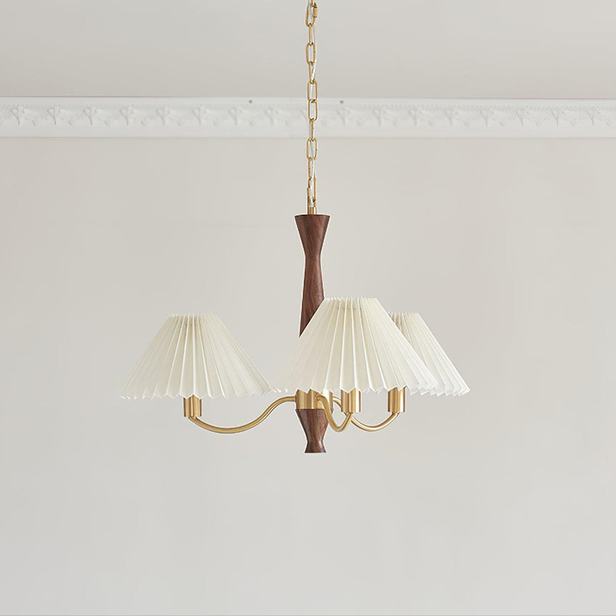 Three ivory pleated shades cluster around the walnut column of this Clérachic chandelier on a plain grey backdrop.