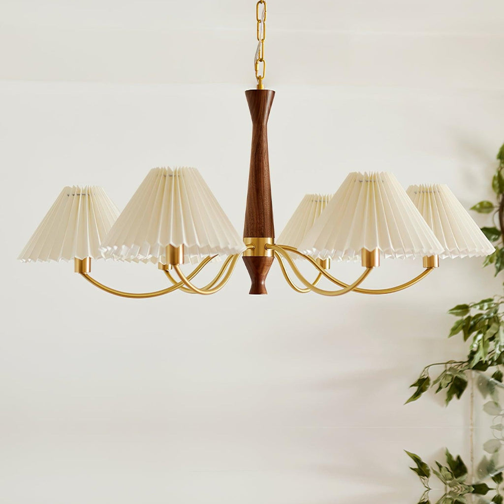 Trailing green leaves sit beside this Clérachic chandelier's row of pleated shades on a plain grey backdrop.