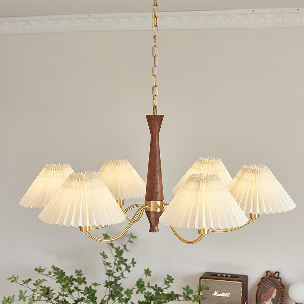 Ceiling moulding runs above this Clérachic chandelier, its pleated shades spread wide over a dresser and framed photo.