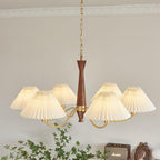 Ceiling moulding runs above this Clérachic chandelier, its pleated shades spread wide over a dresser and framed photo.