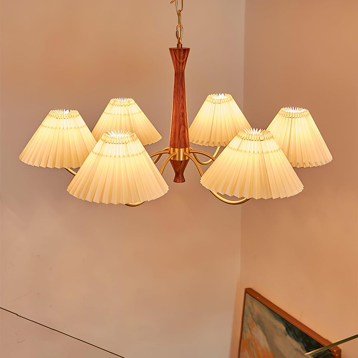 Warm ivory shades on this Clérachic chandelier stand out against a terracotta wall, with a gilt-framed painting visible below.