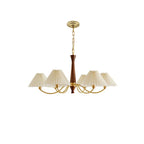Brass arms and pleated shades on this Clérachic chandelier are shown in full against a plain white backdrop.