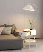 A closer view shows the Clérachic lamp's open drawer and glass vase on the white tabletop next to the grey sofa.