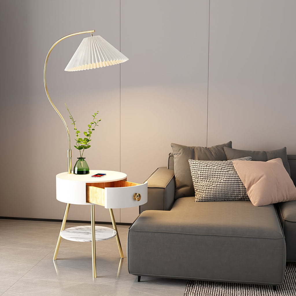 Seen from the other side, the Clérachic floor lamp's curved stem arches over the same white bedside table and grey sofa.