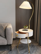 Styled beside a beige sofa on dark flooring, the white Clérachic table lamp holds a small terrarium under its shade.