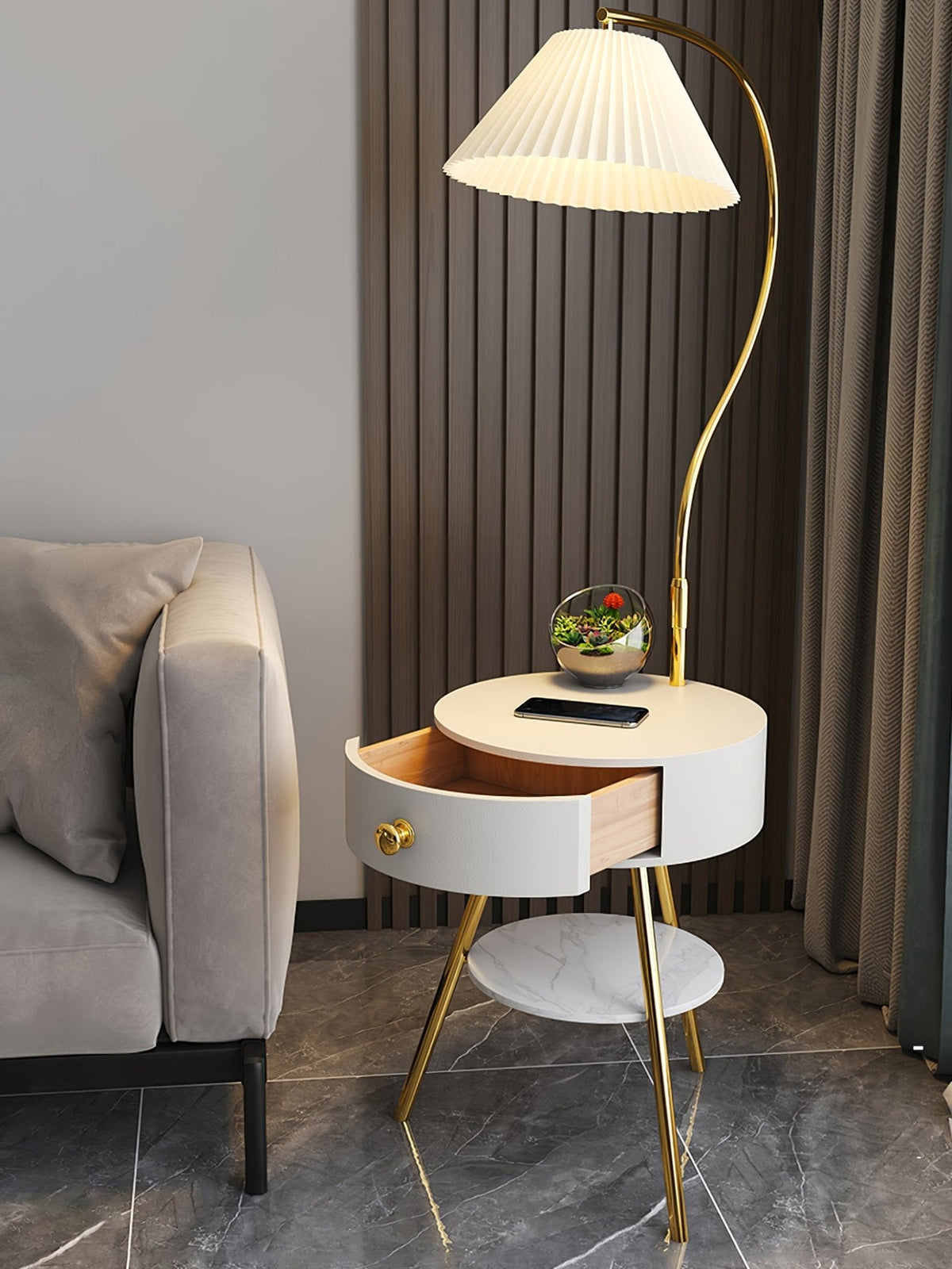Styled beside a beige sofa on dark flooring, the white Clérachic table lamp holds a small terrarium under its shade.