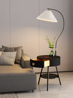 Beside the grey sofa, the black-and-brass Clérachic lamp's drawer sits open under a glass vase of greenery.