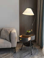 The black-and-brass Clérachic lamp holds a terrarium near a tan sofa, wood-slat wall and dark curtain.
