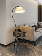 In black, the Clérachic lamp holds a terrarium on its tabletop beside a tan sofa and wood-slat wall.