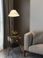 Shown full-height against a curtain and slatted wall, the black Clérachic lamp's marble shelf sits near the sofa edge.