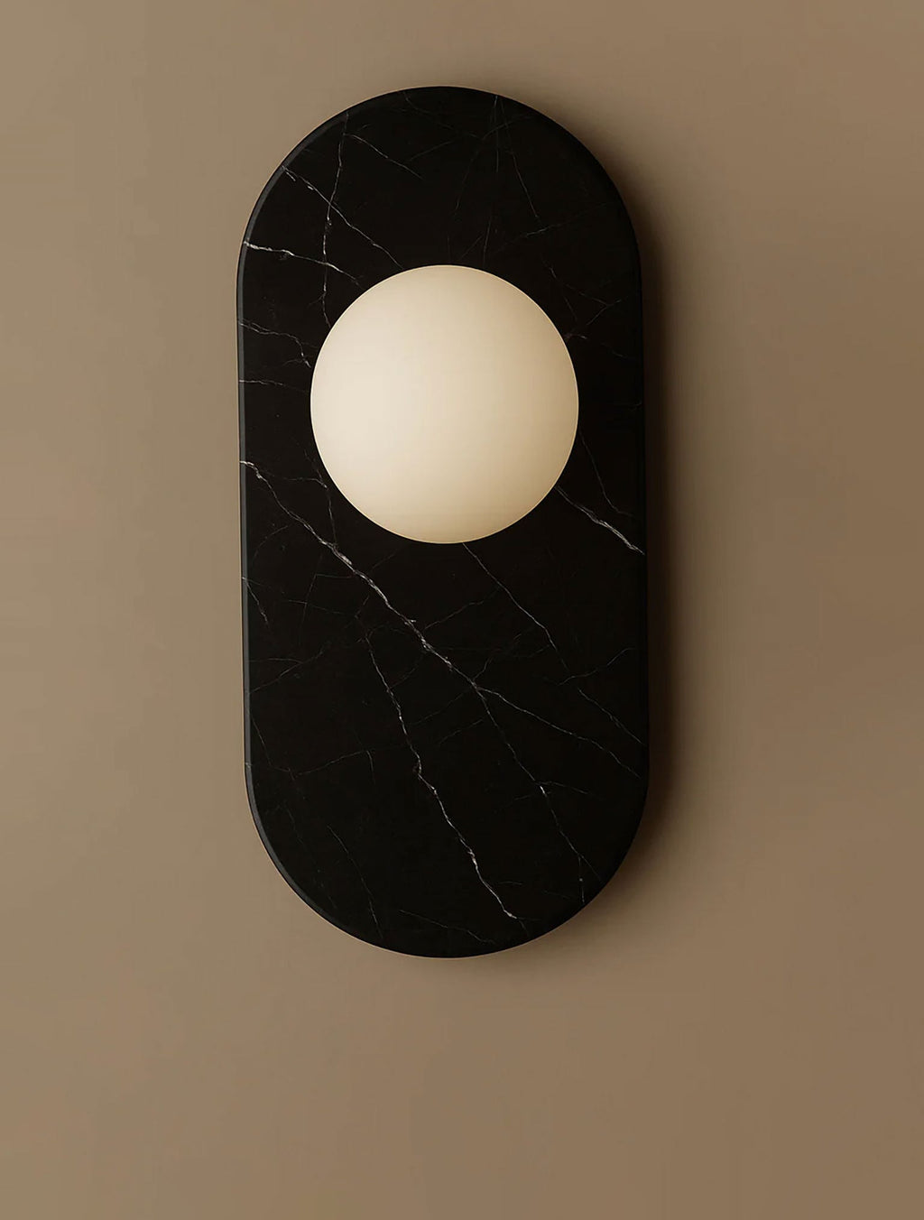 A tightly cropped detail of this Clérachic wall sconce's black marble oval, its edge just meeting the frame's white margin.