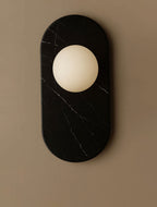 A tightly cropped detail of this Clérachic wall sconce's black marble oval, its edge just meeting the frame's white margin.